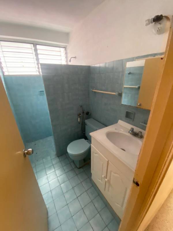 Simple blue-tiled bathroom with walk-in shower and sink in rented commercial space Via Brasil Panama