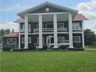 Two-story colonial-inspired luxury home with front columns, balcony, and driveway in Las Perlas David Panama