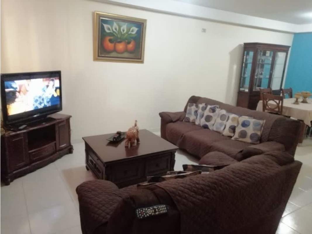 Dining space with table and chairs adjacent to living room in furnished rental house Panama