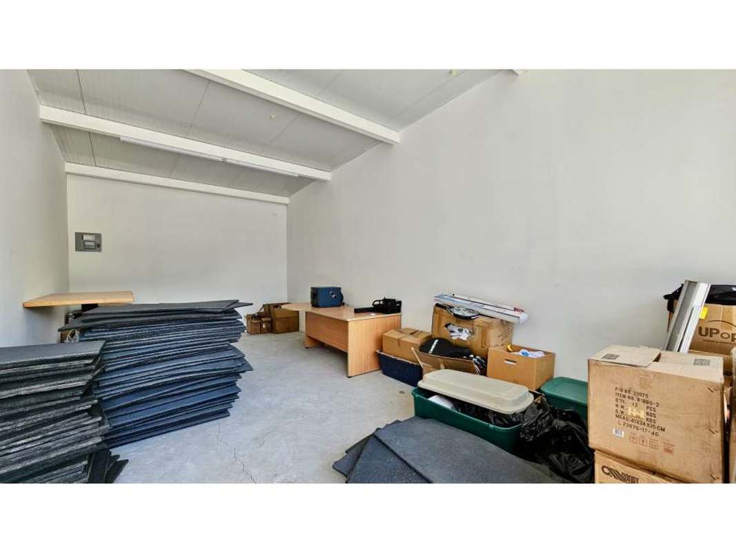 Industrial storage space with stacked materials and office desks for rent in Costa del Este commercial plaza.