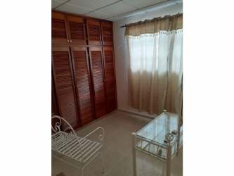 Simple kitchen area with wood cabinets and ceramic counters in Arraijan family house