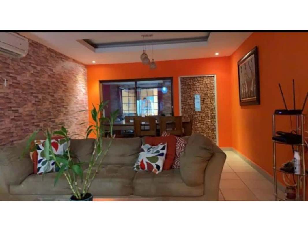 Vibrant living dining area with orange wall, textured accents Brisas del Golf