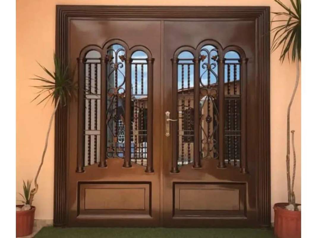 Front door with terracotta walls, arches, and decorative grills in Brisas del Golf