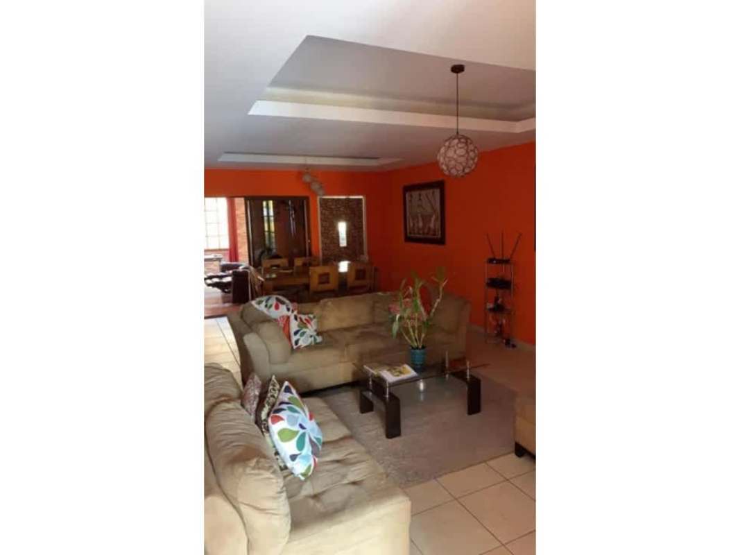 Open concept living and dining with orange accent wall in Brisas del Golf