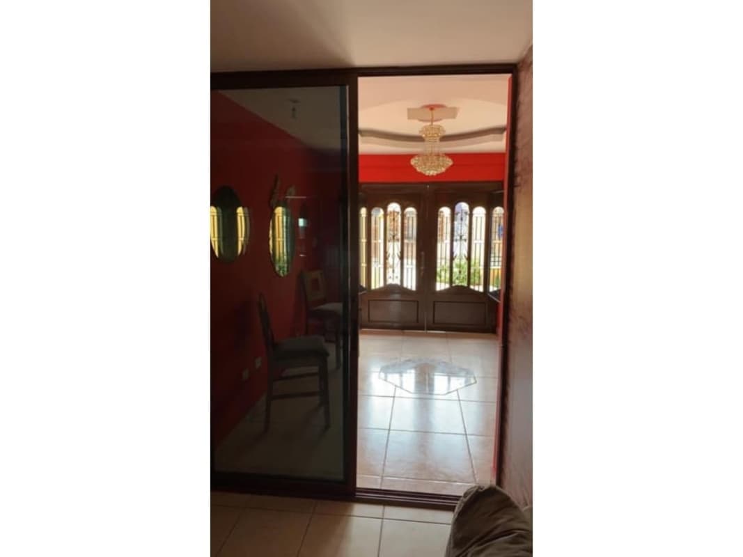 Ornate front door with glass and wrought iron, terracotta wall, and potted plants residential Panama home