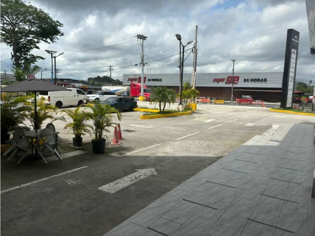 Modern shopping plaza facade with large signage, balcony walkway, and parking spaces in Panama