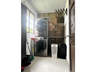 Laundry room with stacked washer dryer and tiled wall in Llano Hermoso house Penonomé