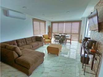 Living dining area with marble floors, large windows, AC, stone accent wall in Playa Blanca Resort Panama condo