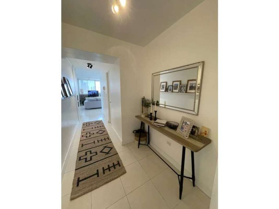 Bright hallway with large mirror, console table, contemporary accents in PH Montemar apartment Panama City for sale