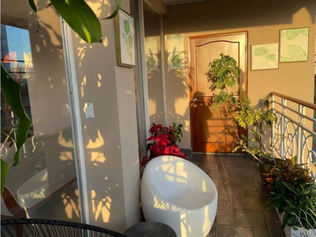 Sunlit balcony with tropical plants and outdoor furniture in PH Quentino San Francisco Panama