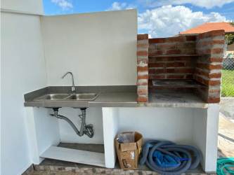 Outdoor kitchen with sink and brick barbecue in backyard San Carlos house