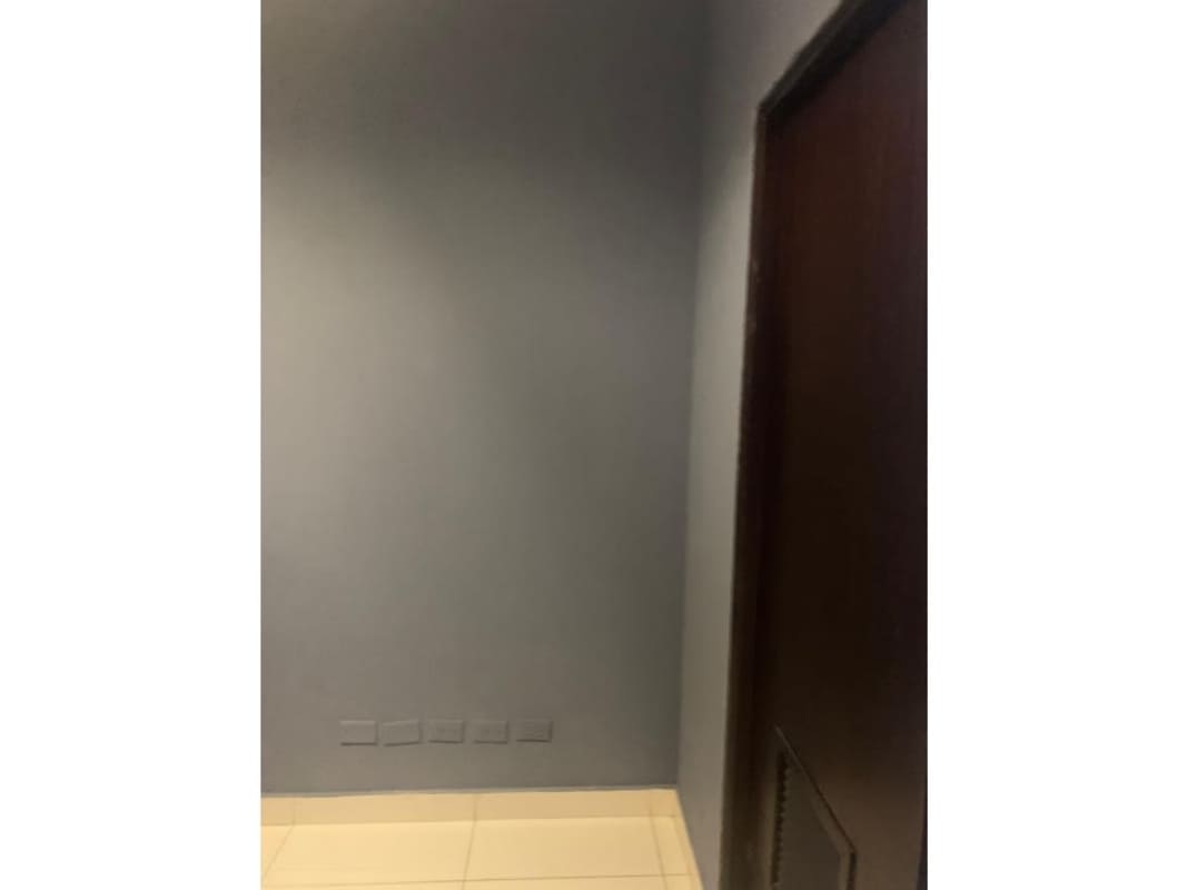 Compact office interior with blue feature wall, cream-colored walls, and tile flooring in Costa del Este