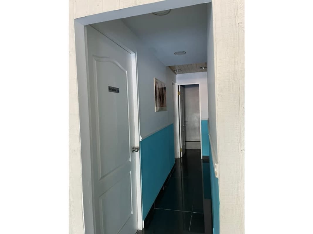 Interior corridor with multiple white doors blue and white walls black tile floor inside commercial plaza Altos de Panama