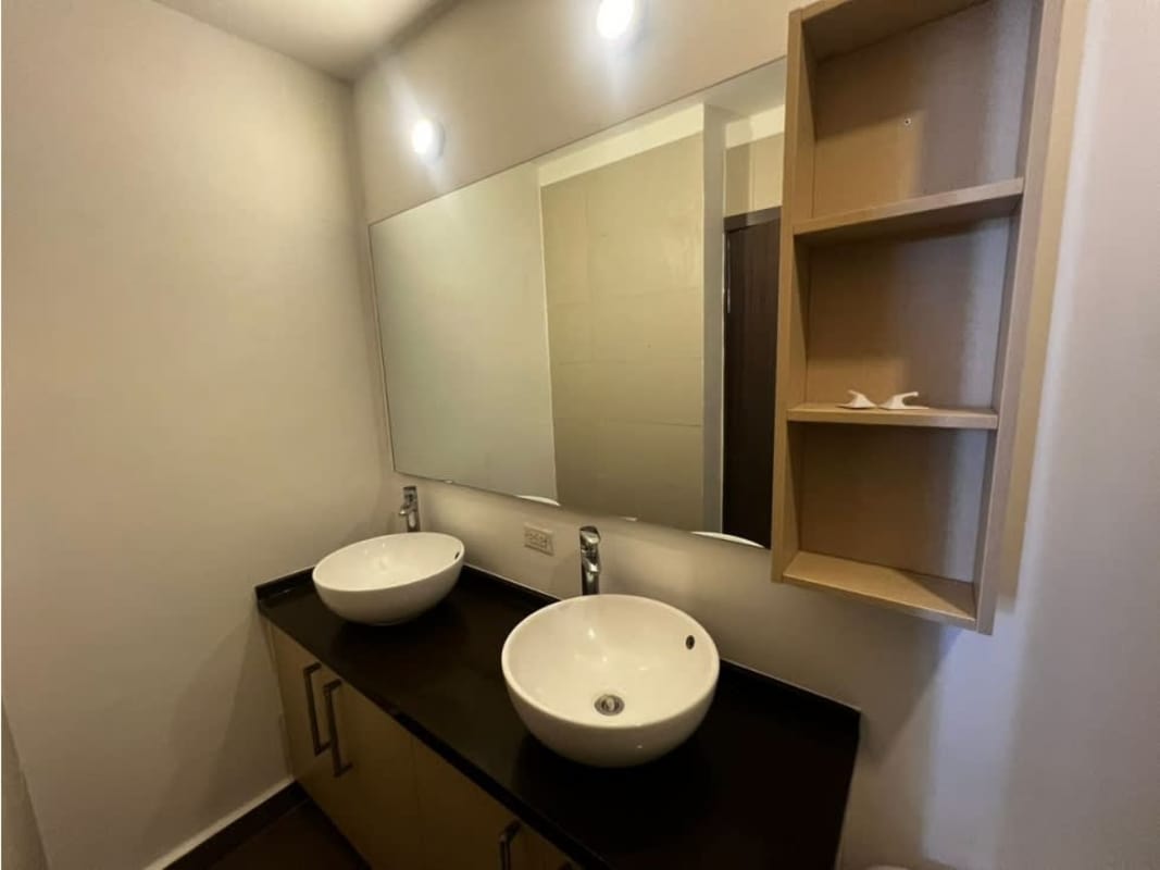 Modern bathroom with double vessel sinks and black countertop in PH Luma Tower Panama City