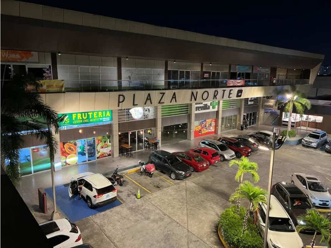 Nighttime illuminated view of Plaza Norte shopping plaza with parking and palm trees Altos de Panamá