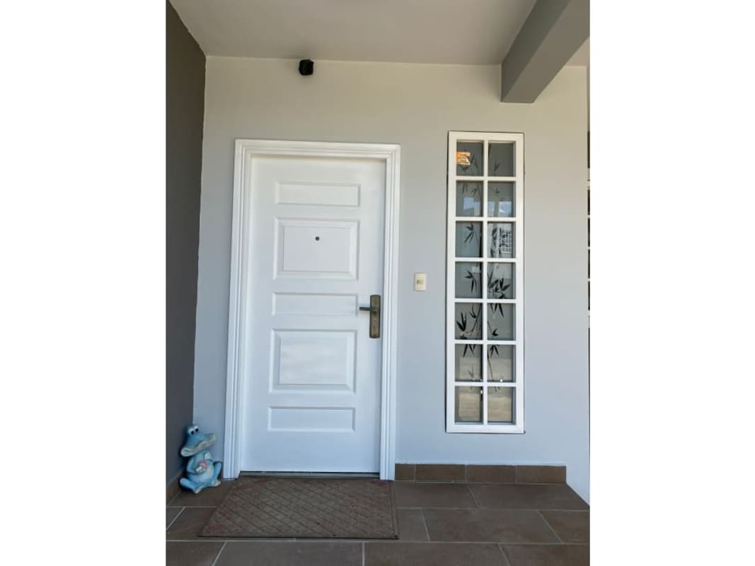 Modern home front porch with glass panels and white door in Panama