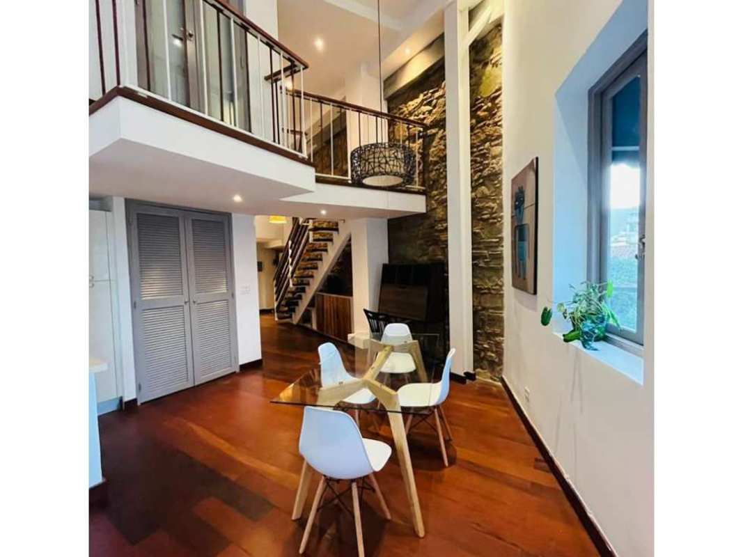 Loft dining area with high ceilings, pendant lights, and exposed brick wall in Casco Viejo Panama apartment