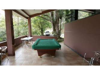 Rustic outdoor entertainment covered patio with pool table, greenery in mountain eco-lodge Cerro Azul