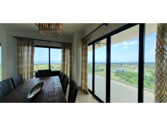 Contemporary dining room with large glass doors and views of ocean and golf at PH Las Olas Vista Mar Panama