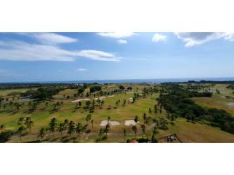 Aerial shot of Vicente Mar golf course, lush fairways, sand bunkers, palm trees with ocean backdrop