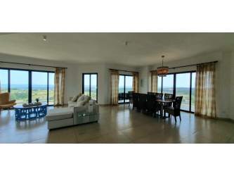 Bright open-plan living dining room with floor-to-ceiling windows offering panoramic ocean and golf views in PH Las Olas Vista Mar Panama