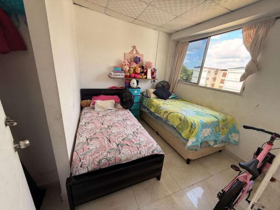 Small bedroom with kids beds, large window, toy shelf and bicycle inside Campo Limberg Panama