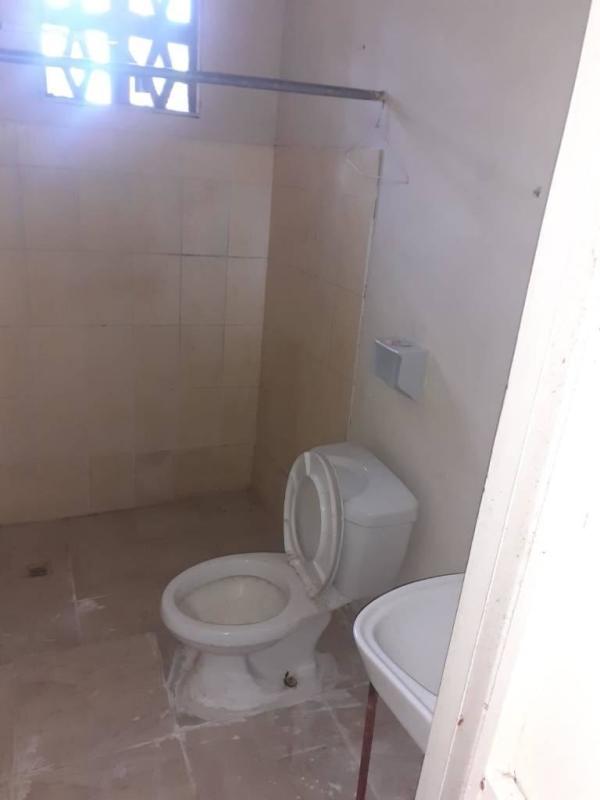 Small bathroom with toilet, sink, tiled walls, and ventilation window in Chepo apartment