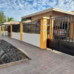Road facing exterior of fenced suburban house with electric gate in David Chiriquí Panama