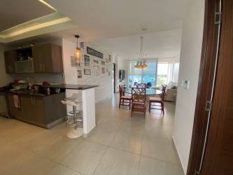 Open kitchen with modern cabinetry, granite counters, breakfast bar and dining space in Playa Blanca condo Panama