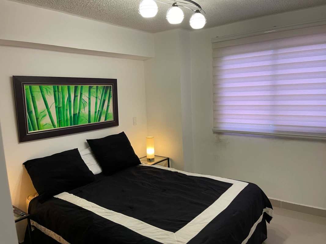 Minimalist bedroom with black and white decor, bamboo art, and natural light in Altamira Gardens Panama City