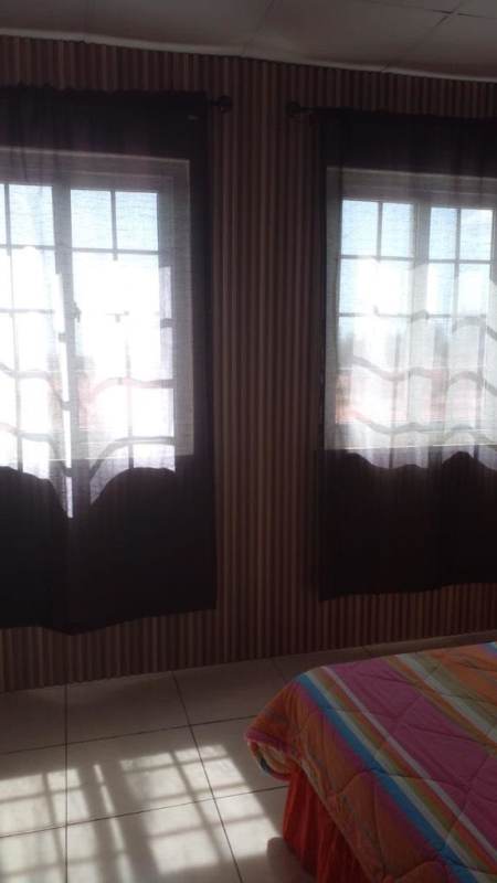 Bright bedroom with striped bedspread and two windows in Villa Lucre Panama apartment rental