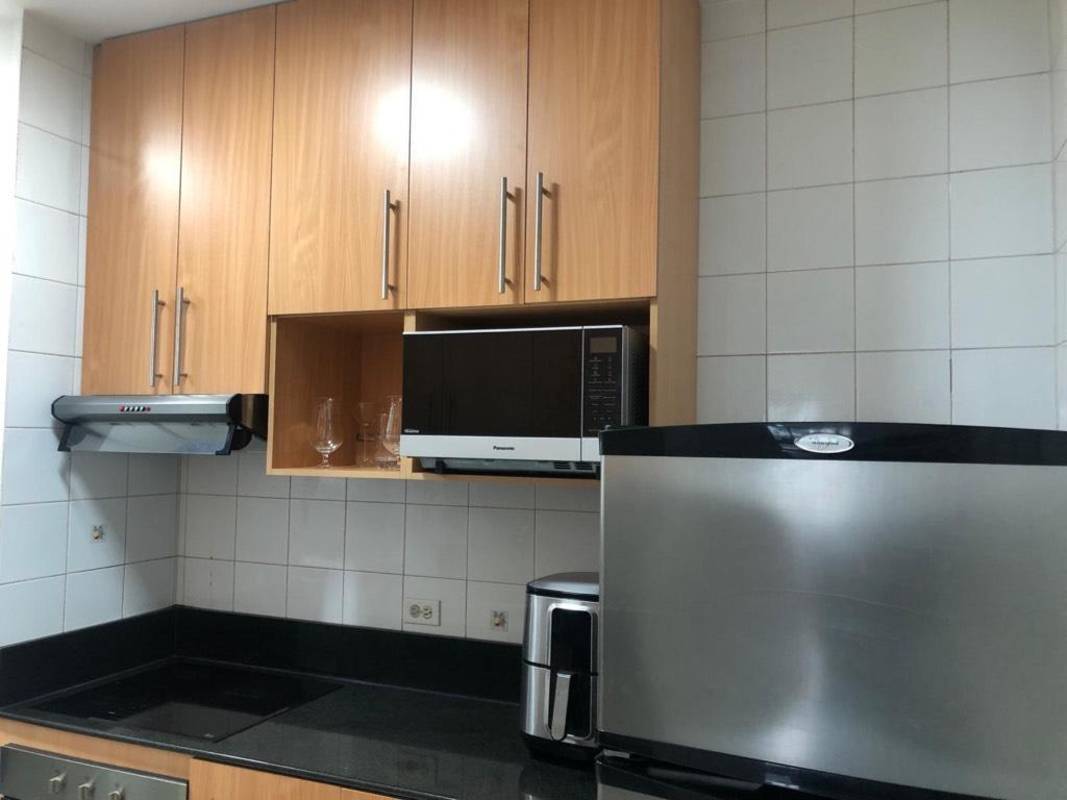 Full kitchen with wood cabinets, granite counters, and appliances in Marbella city apartment Panama