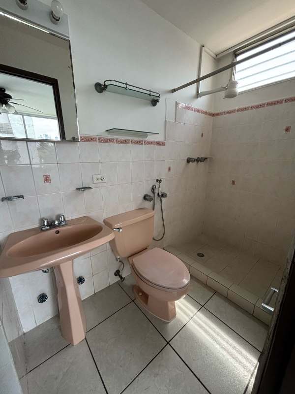 Bathroom with walk-in shower, pedestal sink, mirror and tile walls at PH Via Porras San Francisco Panama City