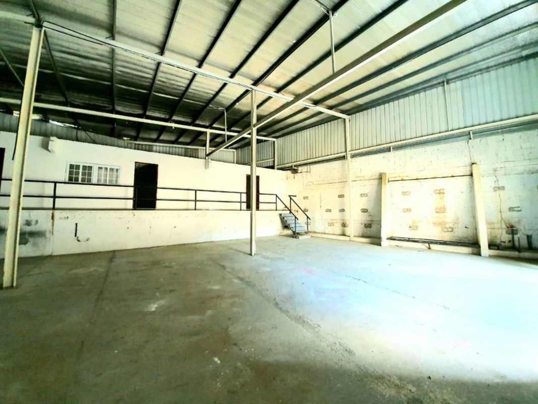 Wide open industrial warehouse view with concrete floor, metal roofing and raised platform
