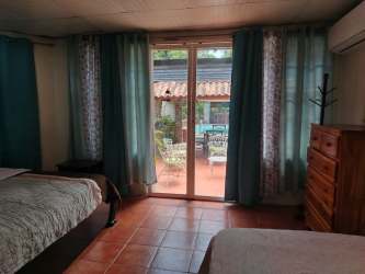 Stone walls, covered porch, terracotta roof, green lawn at Playa Malibu beach rental Panama