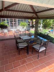Terracotta tiled outdoor patio with dining table, plants, pergola and garden landscaping at Playa Malibu rental Panama