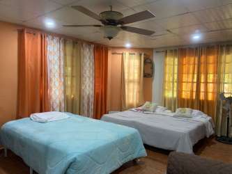 Artificial grass yard, patio set with glass table and swing in lush garden of Playa Malibu vacation home Panama