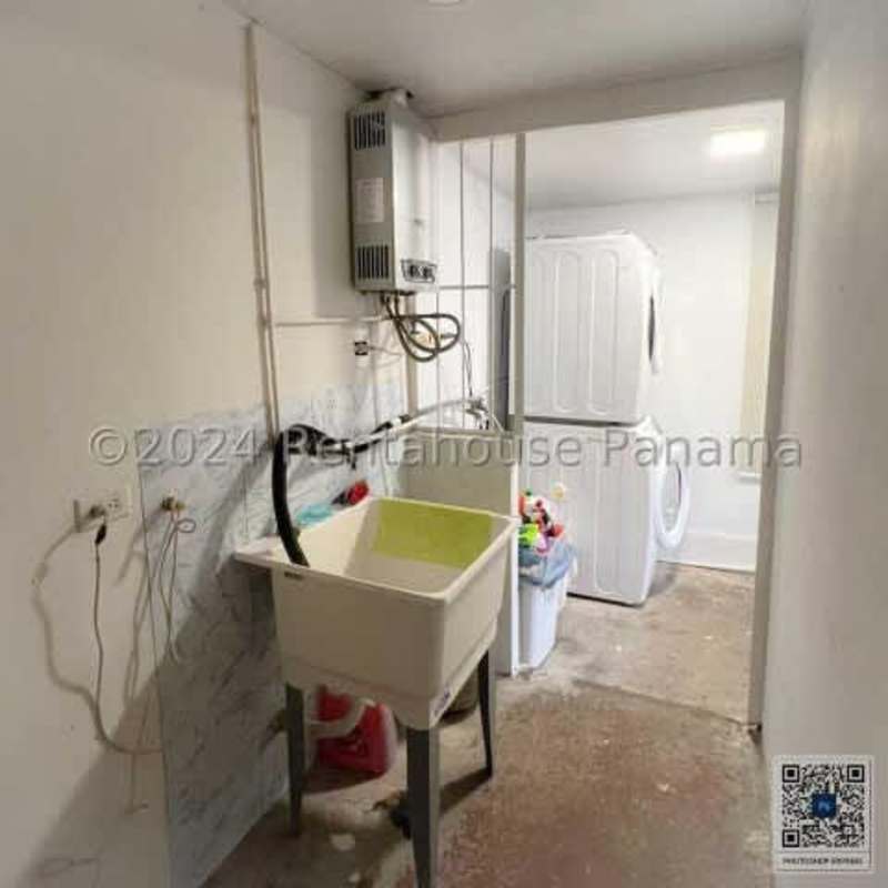 Laundry room with stacked washer dryer utility sink tile floor in Chanis house Panama