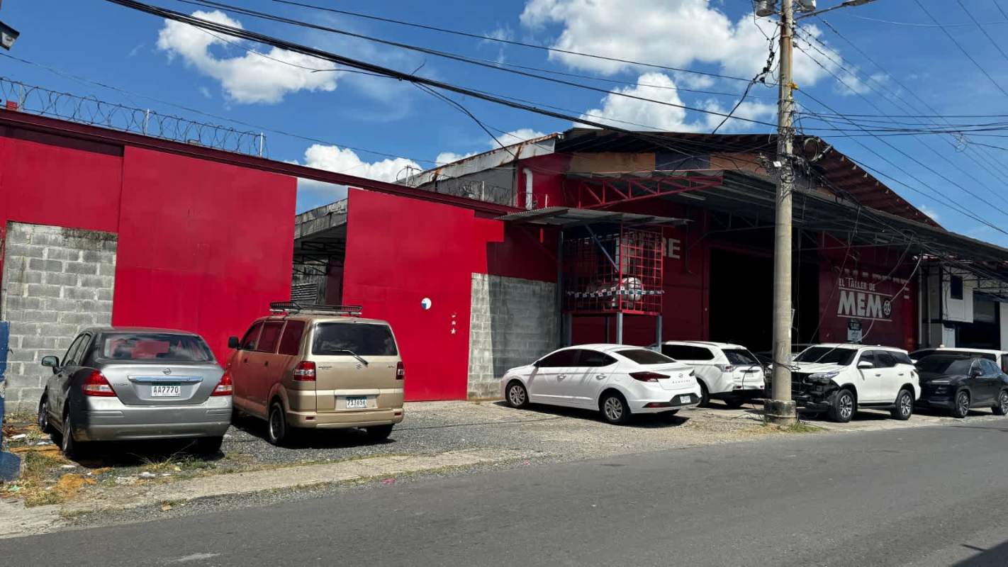 Streetfront industrial complex with red-painted walls and fenced security in Panama City Rio Abajo
