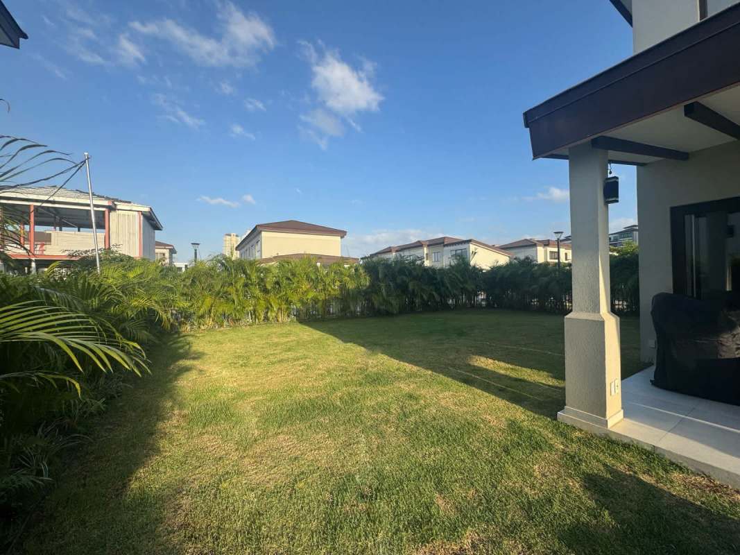 Large backyard with lush green lawn and covered outdoor patio in The Woods Santa Maria Panama