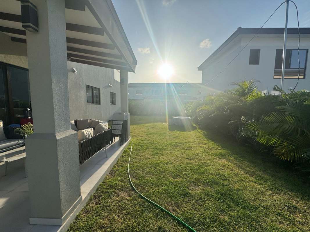 Backyard with green lawn, covered patio and privacy hedges in The Woods Santa Maria luxury house rental