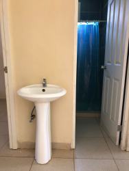 Minimalist bathroom pedestal sink tiled floor walk-in shower in duplex La Chorrera Panama