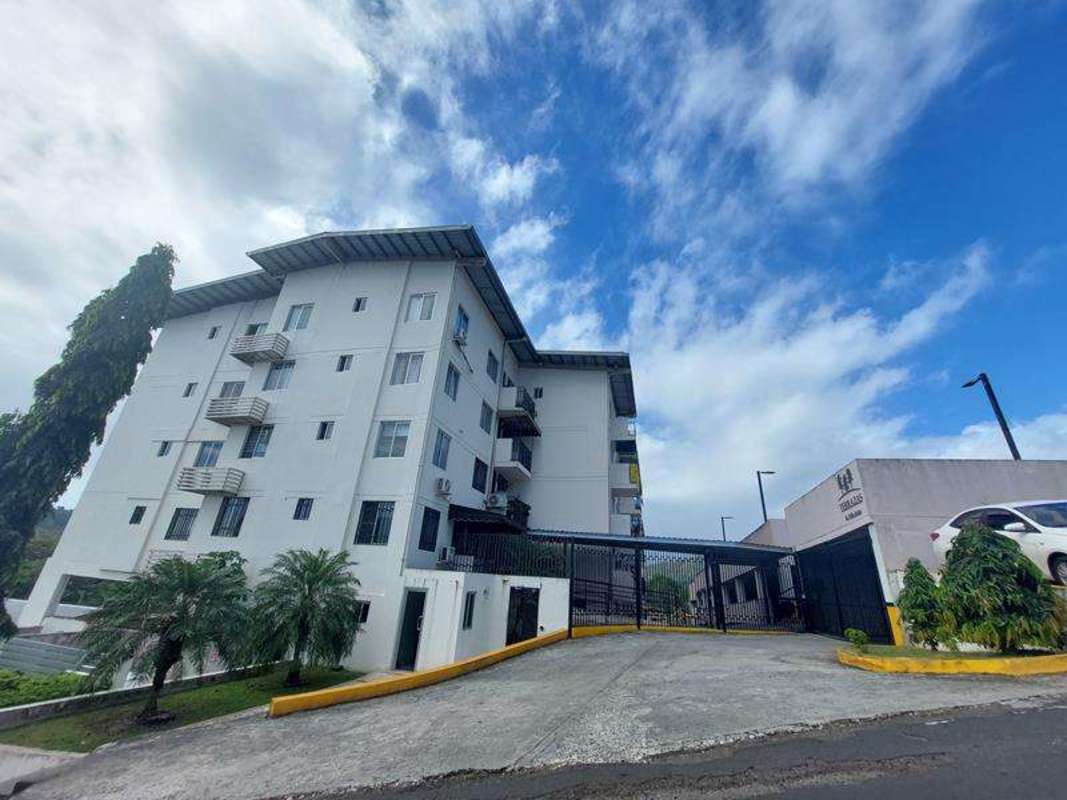 Exterior of mid-rise white apartment building with balconies and gated entrance PH Terrazas de Vía Zaita
