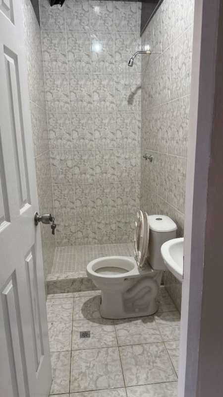 Simple bathroom with toilet, pedestal sink, shower and tiled walls La Locería affordable rental