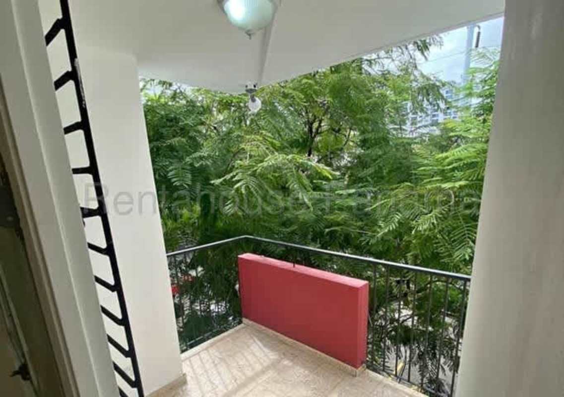 Balcony with beige tiles, black railing facing green trees Parque Lefevre apartment Panama