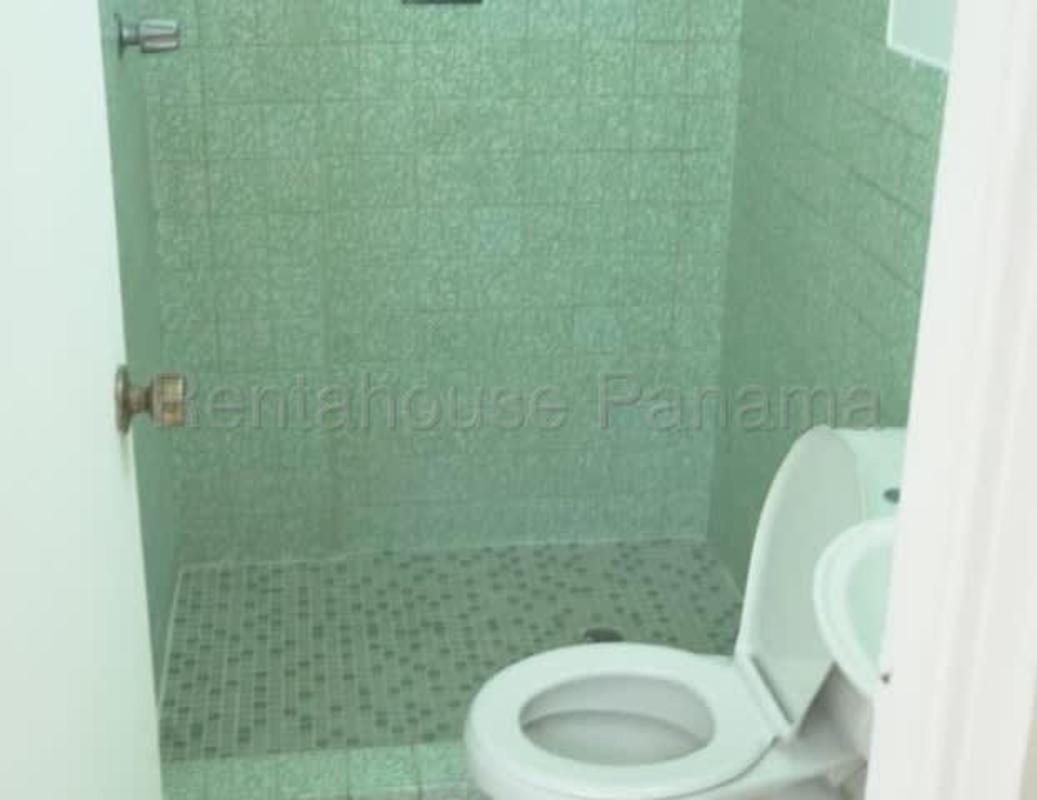 Bathroom with green tiled walls, walk-in shower, white toilet and sink Parque Lefevre apartment Panama
