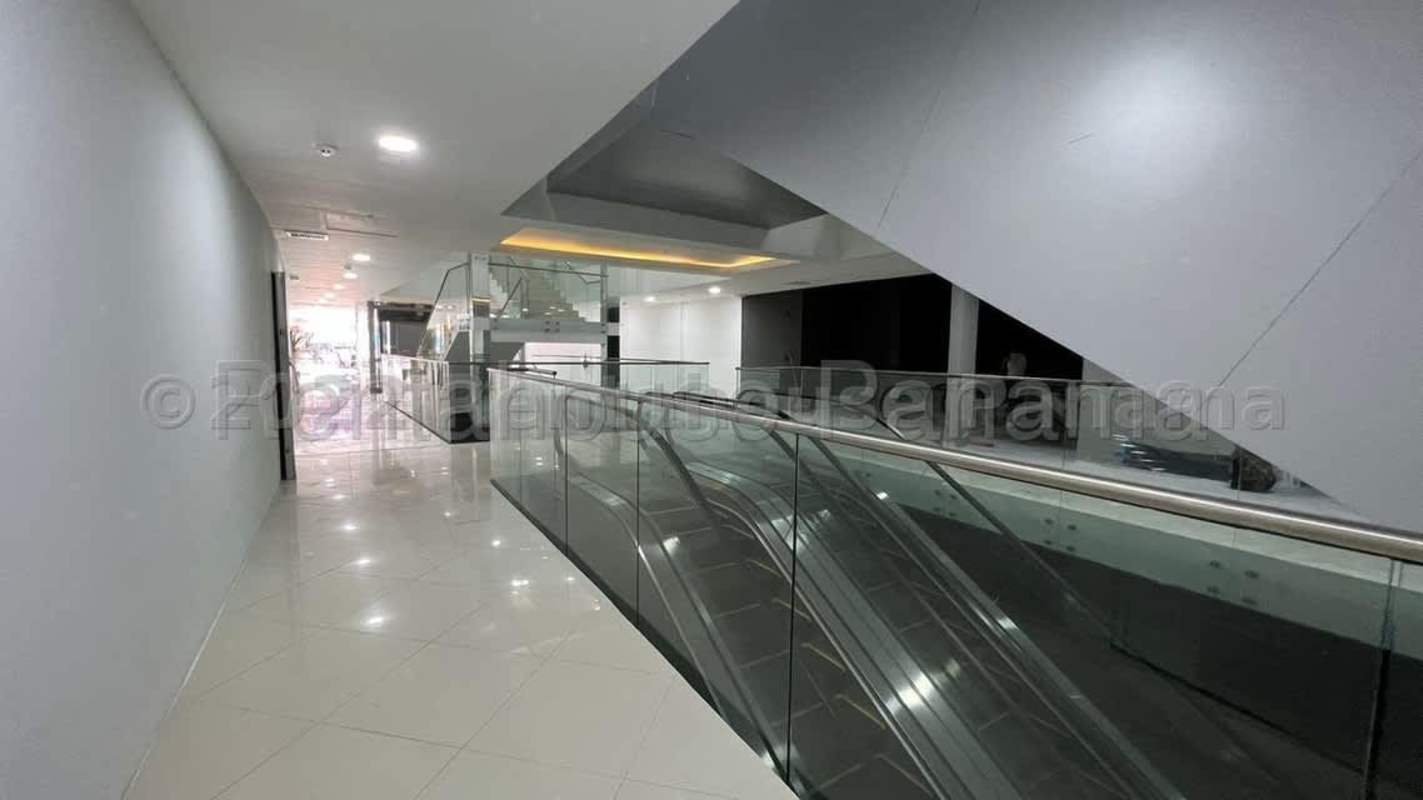Interior corridor with escalator and glass railing inside PH Plaza España on Vía España