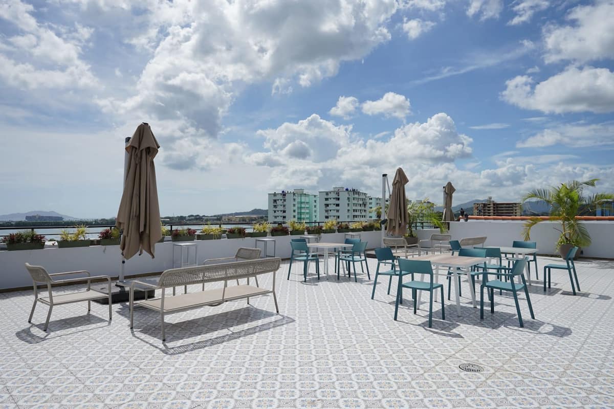 Scenic rooftop terrace with seating and umbrellas overlooking Panama City and Pacific Ocean at PH La Cuadra