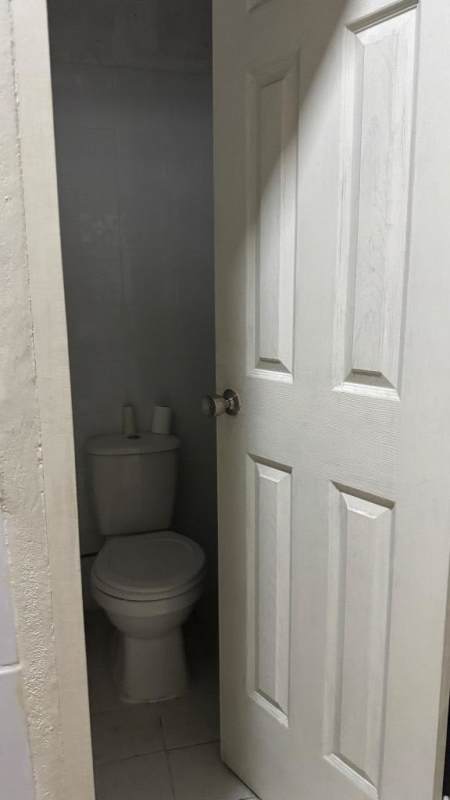 Small enclosed bathroom with toilet behind partial door at commercial lease Panama