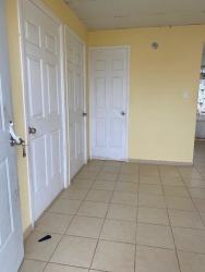 Empty bedroom with tiled floor, light yellow walls, window with security bars in Barrio Balboa